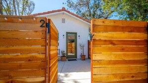 A wooden gate with the number 2, leading to a building with a green door and a small potted plant beside it. - Stunning Guesthouse with Private Entry & Courtyard (Santa Maria)