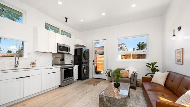 A modern kitchen with white cabinets, stainless steel appliances, and a large window. - Stunning Guesthouse with Private Entry & Courtyard (Santa Maria)