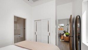 A modern bedroom with a large bed, a wardrobe, and a mirror. - Stunning Guesthouse with Private Entry & Courtyard (Santa Maria)