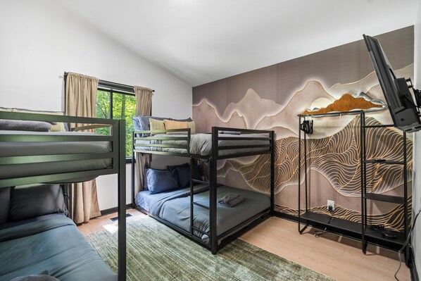 A bunk bed room with a television on a stand, a window with curtains, and a wall with a wave pattern design. - Welcome to The Basye Swan (Basye)