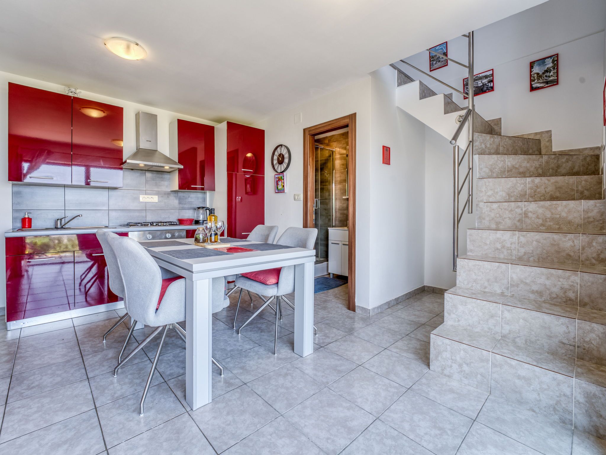 A modern kitchen with red cabinets and a dining area with a white table and chairs.