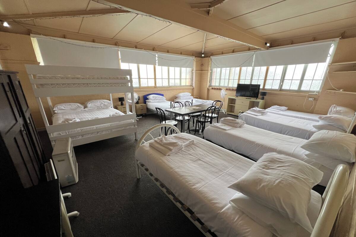 A hotel room with bunk beds, a dining table, chairs, a TV, and a desk.