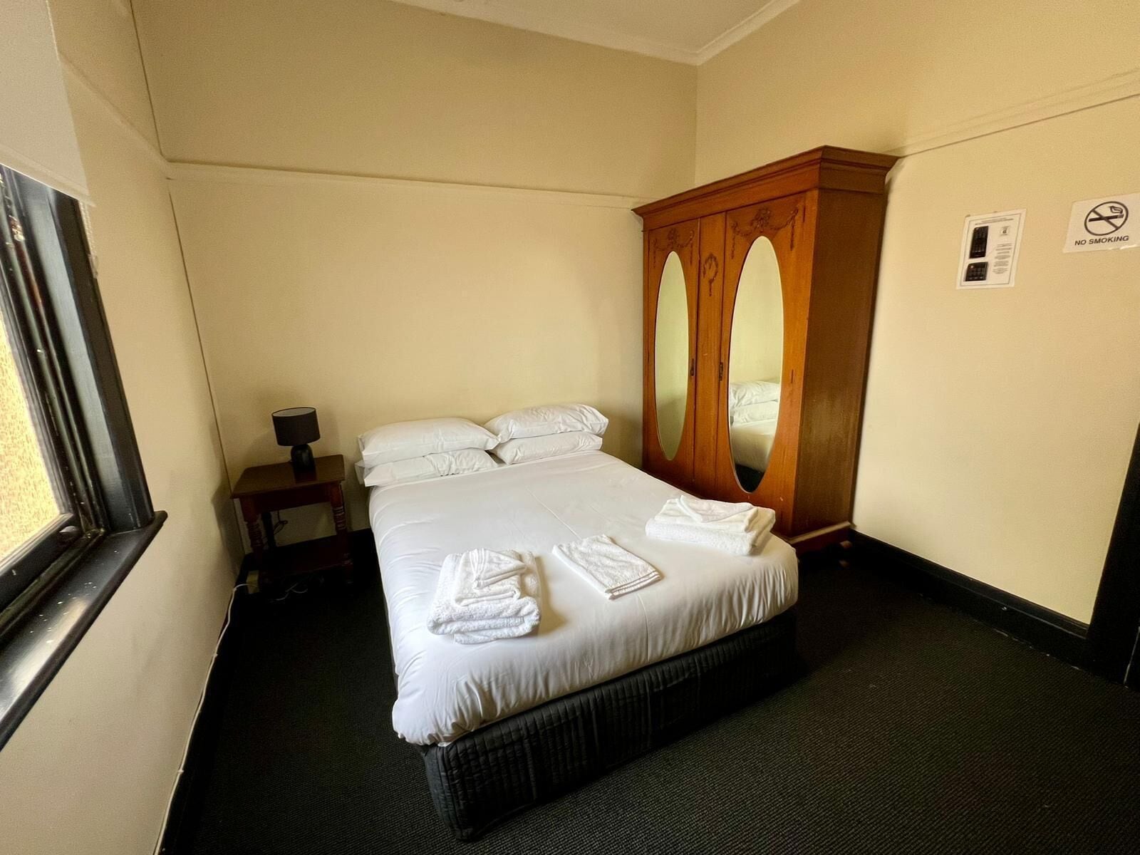 Una habitación de hotel con cama, mesita de noche, espejo y ventana.