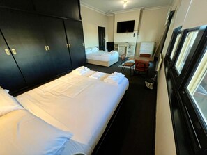 A hotel room with a bed, a desk, a chair, a television, and a window. - Gordon Hotel (Goulburn)