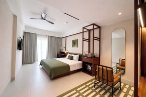 A hotel room with a bed, a desk, a chair, a ceiling fan, and a large mirror. - Magnolia Boutique Hue (Hue)