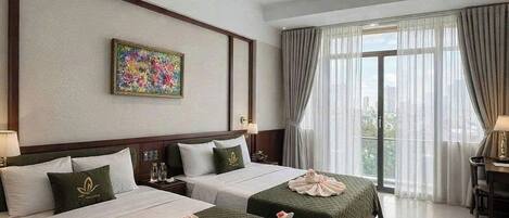Habitación de hotel con dos camas, ventilador de techo, un cuadro en la pared y vistas por la ventana.