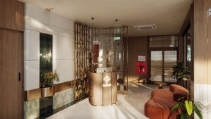 A modern reception area with a marble reception desk, a wooden partition, and a seating area with a plant. - Magnolia Boutique Hue (Hue)