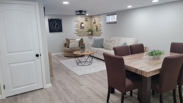 Ein modernes Wohnzimmer mit Essbereich, ausgestattet mit einer weißen Tür, einer Sofagarnitur, einem Couchtisch und einem Esstisch mit Stühlen.