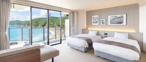 Una habitación de hotel con dos camas, un ventanal con vista al mar y un balcón.
