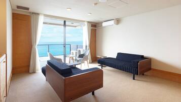 A modern hotel room with a balcony, a sofa, a chair, and a small table.