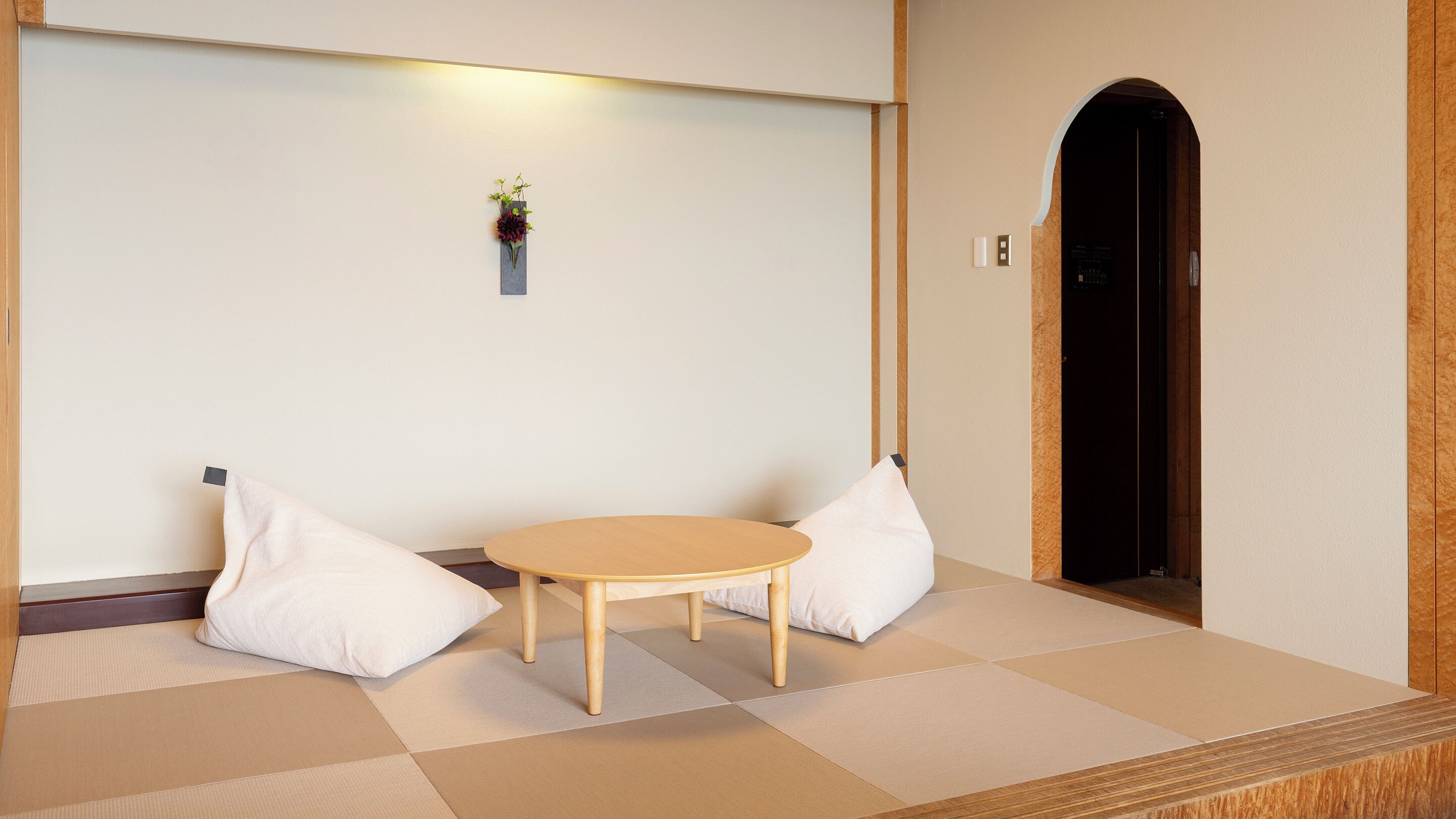 Una habitación japonesa tradicional con suelo de tatami, una mesa de madera baja y dos almohadones.