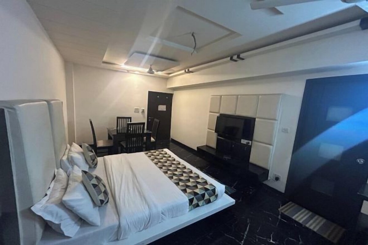 A modern hotel room with a bed, a TV, a desk, and a chair.