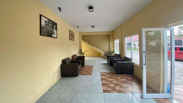 A hotel lobby with a staircase, seating area, and a glass door entrance. - Hotel Warna (Palopo)