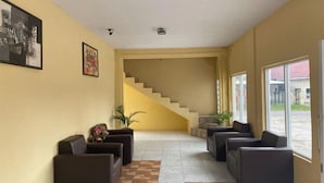 A spacious lobby with a staircase, comfortable seating, and large windows. - Hotel Warna (Palopo)