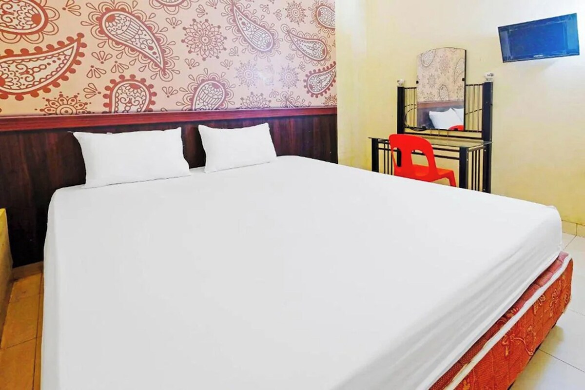 Una habitación de hotel con una cama grande, una silla roja, un escritorio y un espejo.