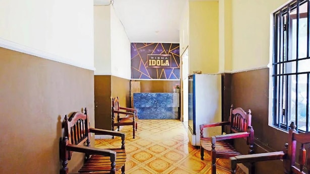 A hallway with wooden chairs, a reception desk, and a patterned floor. - Guest House Idola Palopo (Palopo)