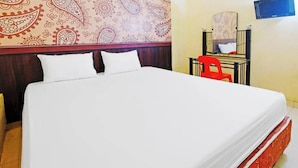 A hotel room with a large bed, a red chair, a desk, and a mirror. - Guest House Idola Palopo (Palopo)