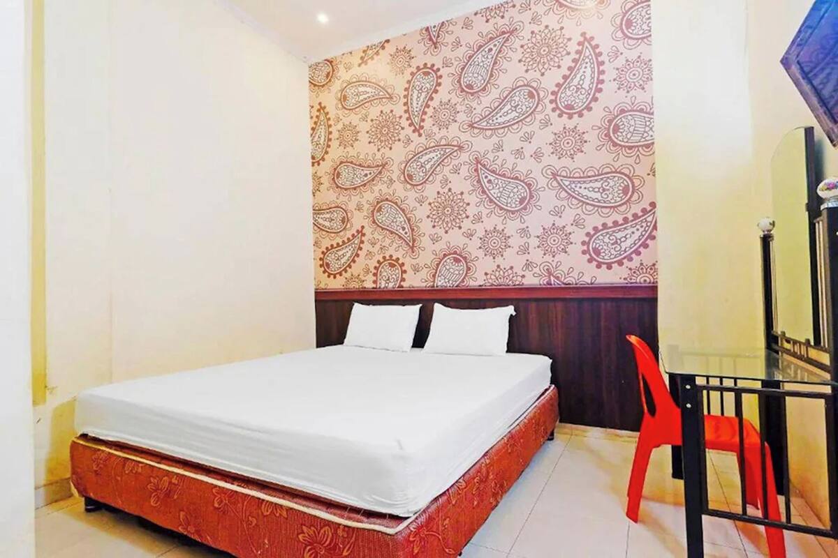 Une chambre à coucher avec un lit, une chaise rouge et un mur à motifs.