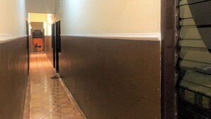 A hallway with patterned flooring, a staircase on the right, and a door at the end. - Guest House Idola Palopo (Palopo)