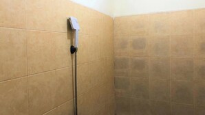 A shower area with beige tiles and a handheld showerhead. - Guest House Idola Palopo (Palopo)