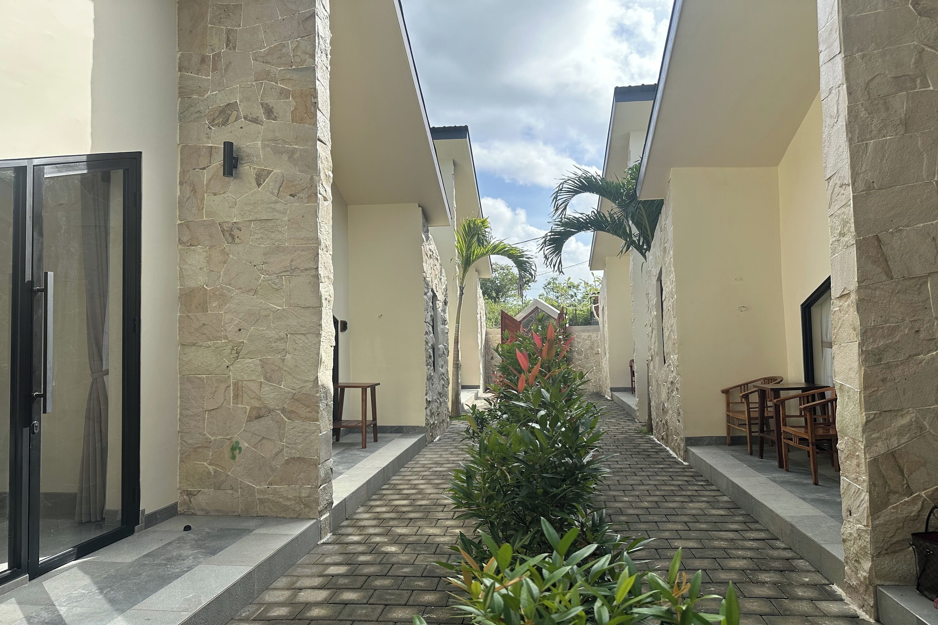 A corridor with stone walls, a central planter, and wooden furniture.