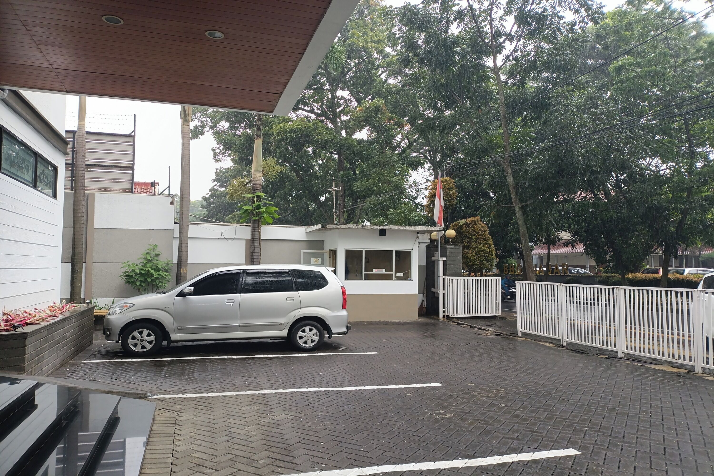 Un espace de stationnement où une voiture blanche est garée devant un immeuble à la façade blanche et beige.