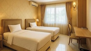 A hotel room with two beds, a desk, and a chair. - Cipto Apartment (Bandung)