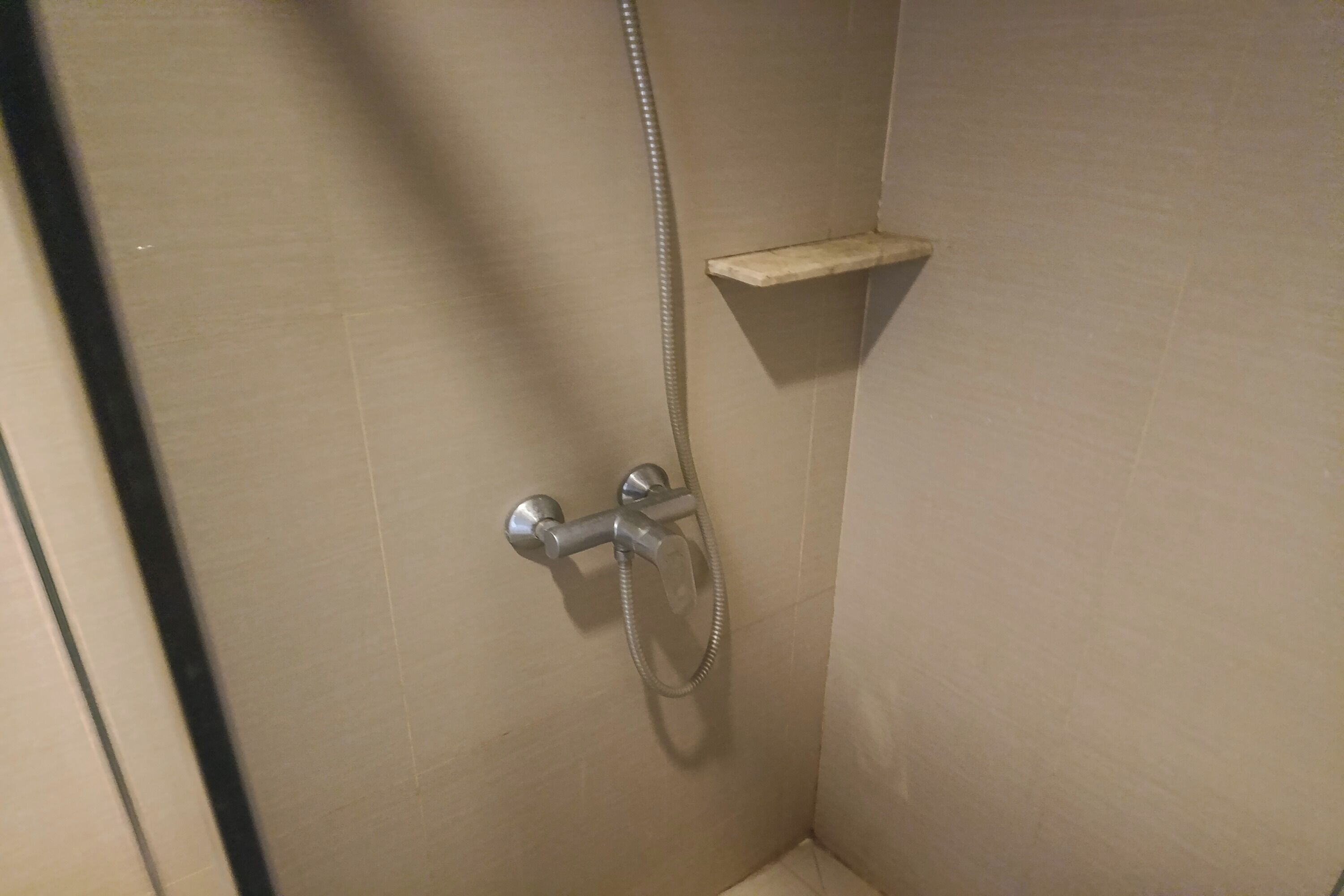 Un área de ducha con cabezal de ducha de mano y control empotrado en la pared.