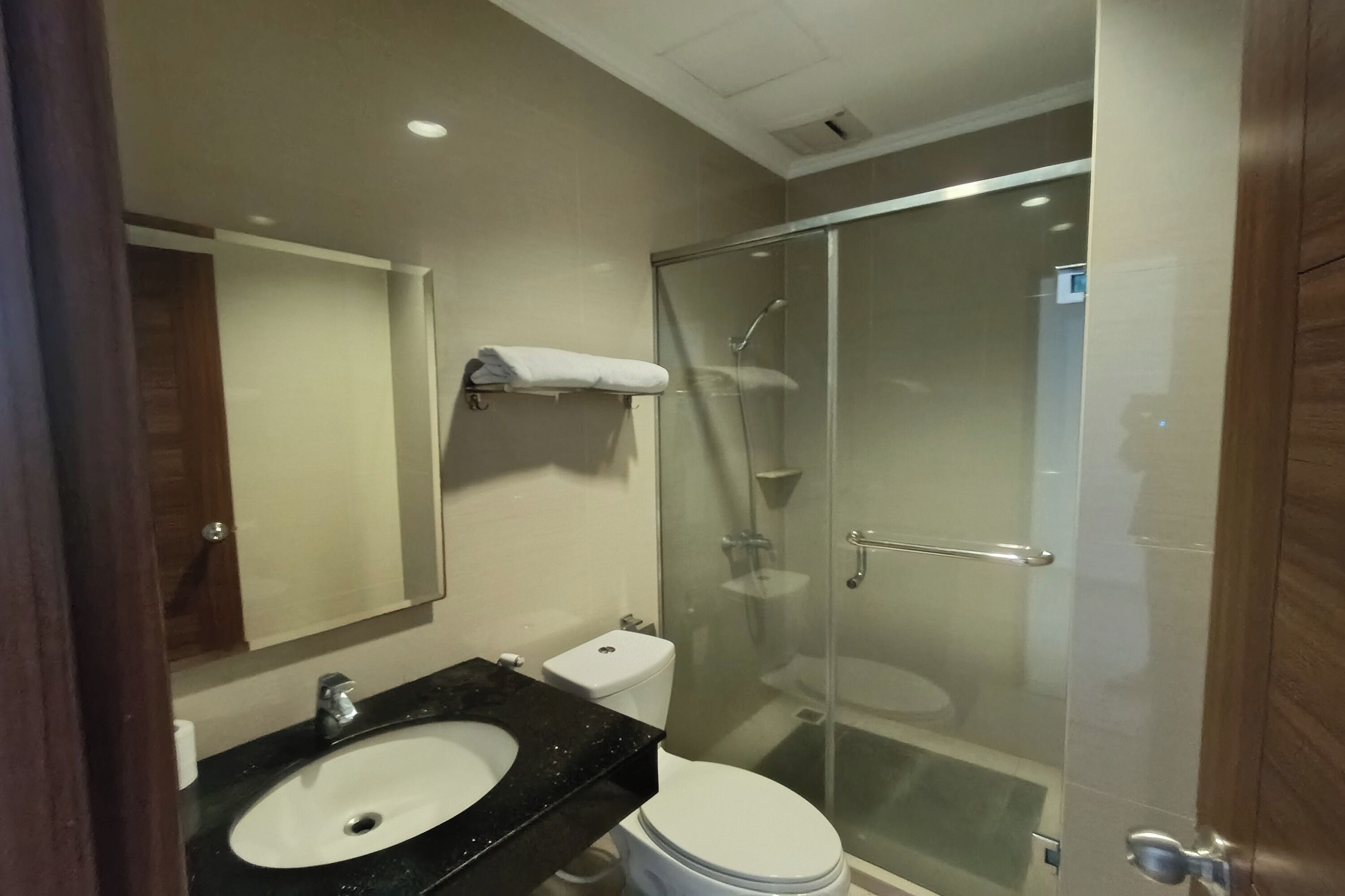 Een moderne badkamer met een douchecabine van glas, een witte wastafel en een toilet.