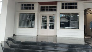 A building entrance with a set of steps leading up to a door with barred windows. - Cipto Apartment (Bandung)