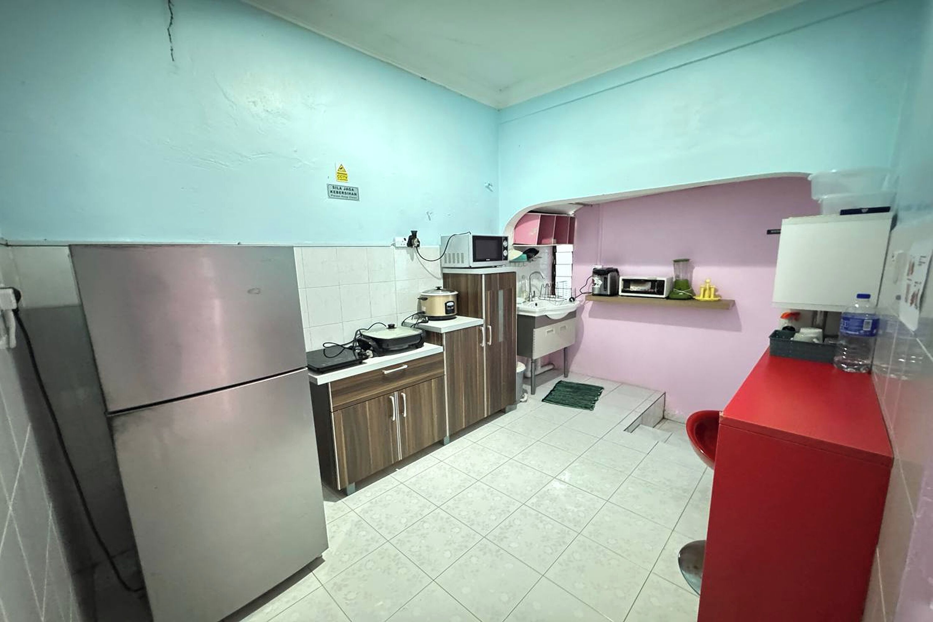 A compact kitchen with a refrigerator, microwave, sink, and a small countertop area.