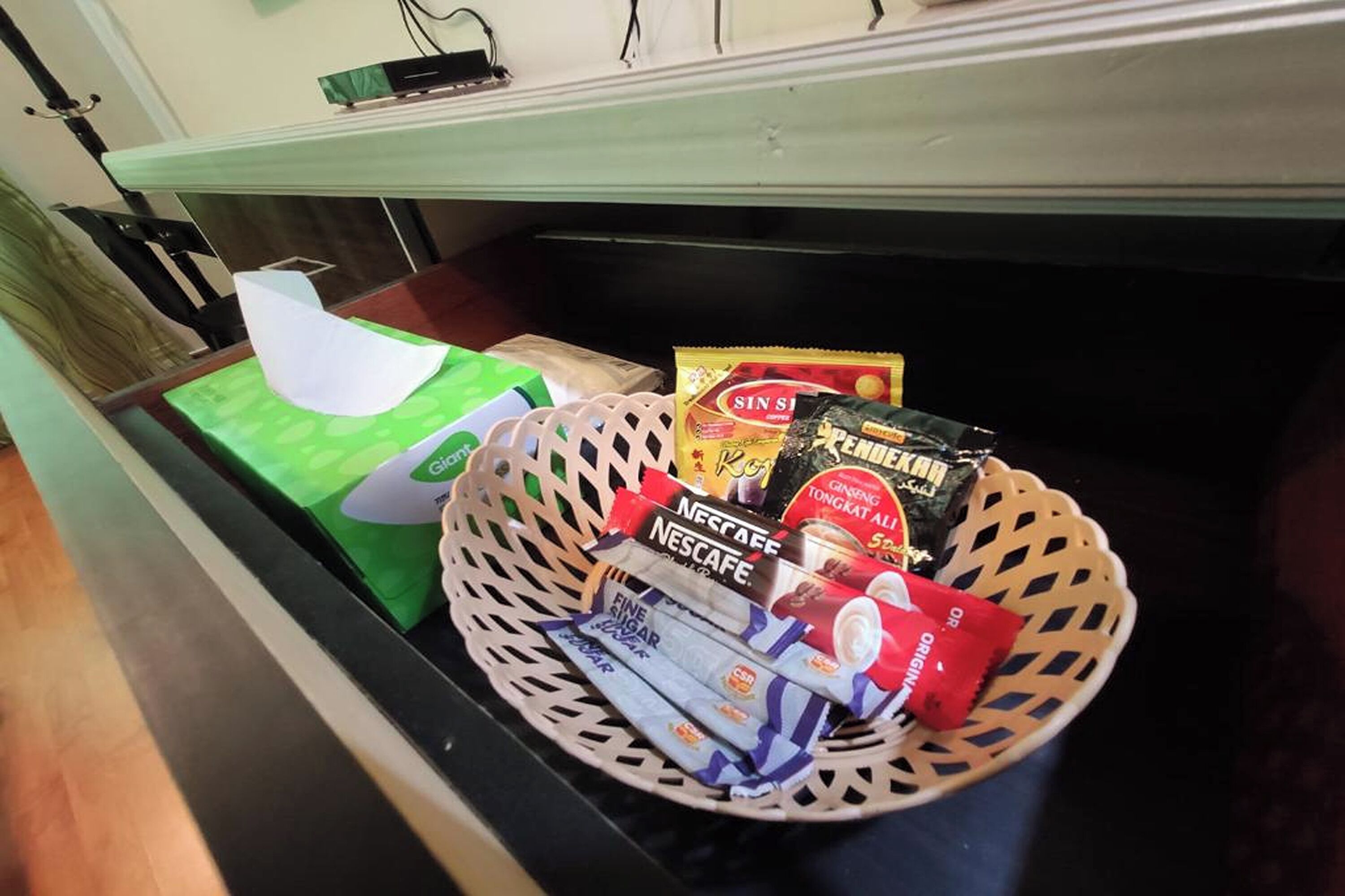 A basket containing Nescafe coffee packets, a tissue box, and a packet of Sin Sio.
