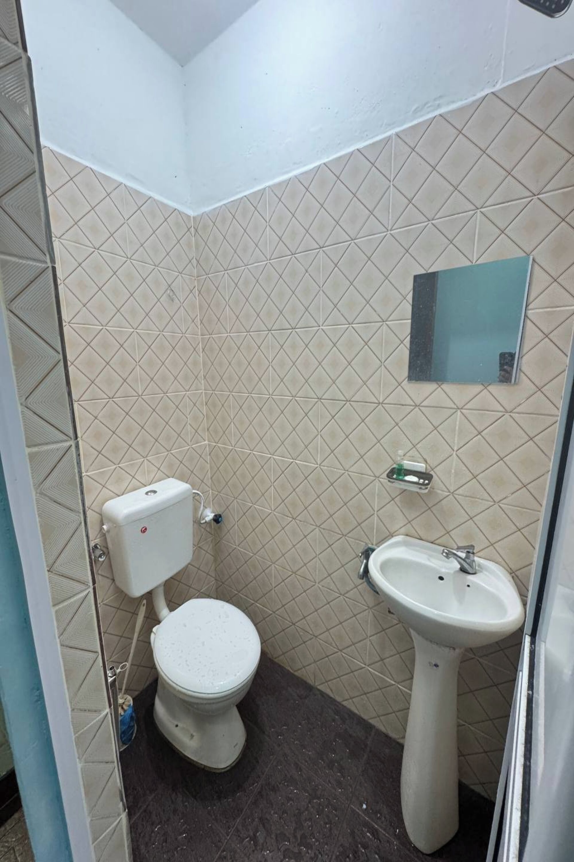 A small bathroom with a toilet, sink, and a mirror on the wall.