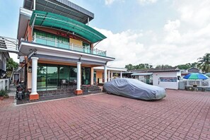 Un edificio con ingresso coperto, una zona salotto esterna coperta e un'auto al coperto.