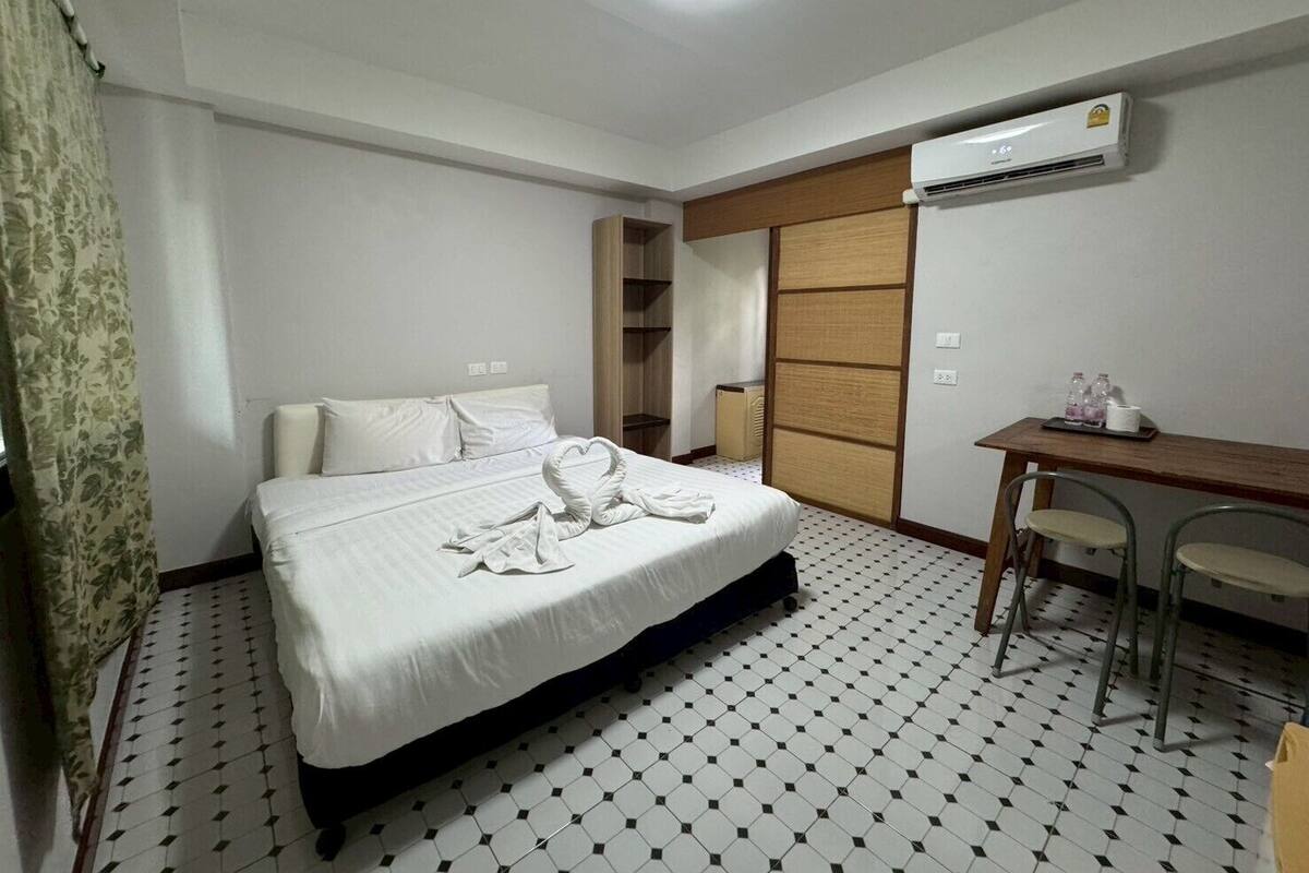 A hotel room with a bed, a desk, and an air conditioner.