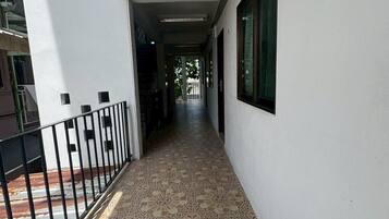 A corridor with patterned flooring, a metal railing, and a window on the right.