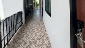 A corridor with patterned flooring, a metal railing, and a door with a keypad lock. - Sukhum Suvarnabhumi Airport Guest House (Bangkok)