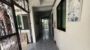 A corridor with a tiled floor, a metal gate, and a wall-mounted picture. - Sukhum Suvarnabhumi Airport Guest House (Bangkok)