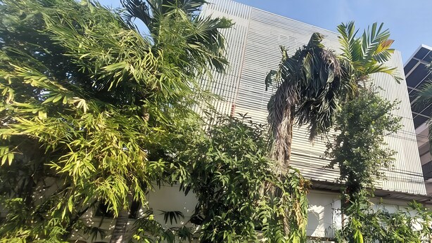 Un edificio con fachada de metal corrugado y abundante follaje delantero.