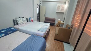 Una habitación con dos camas, un sofá, una mesita y un armario.