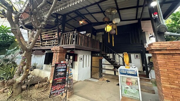 A rustic building with a balcony, a staircase, and a sign for cold drinks. - Nearthepark Boutique House (Chiang Mai)