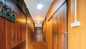 A hallway with wooden paneling and a wooden floor, leading to a door with a number plate. - Nearthepark Boutique House (Chiang Mai)