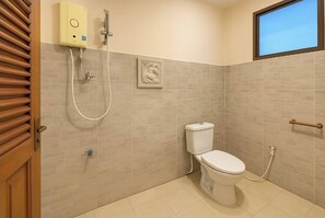 Een badkamer met een toilet, een douche en een raam.