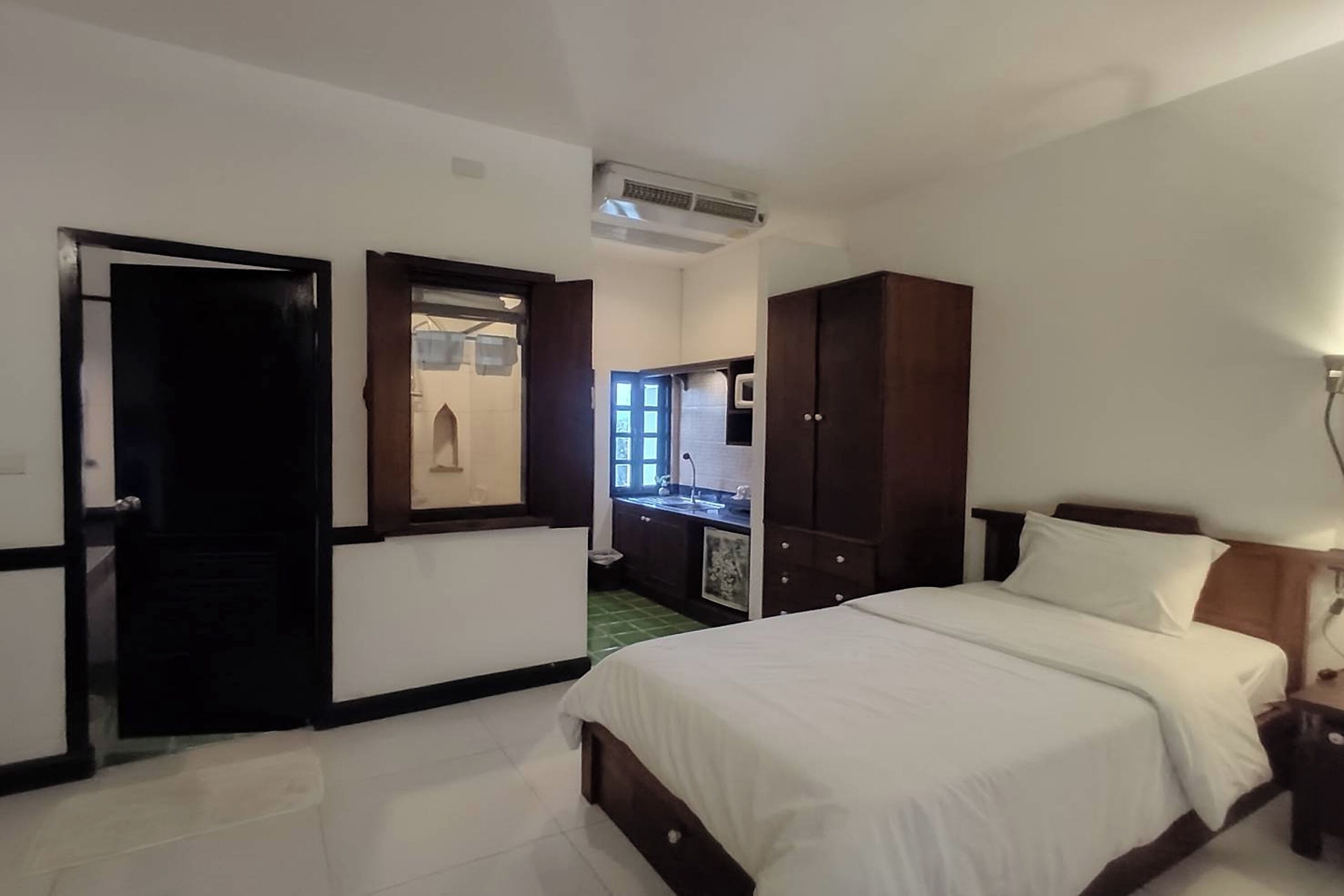 A hotel room with a bed, a wardrobe, a desk, and a bathroom visible through an open door.