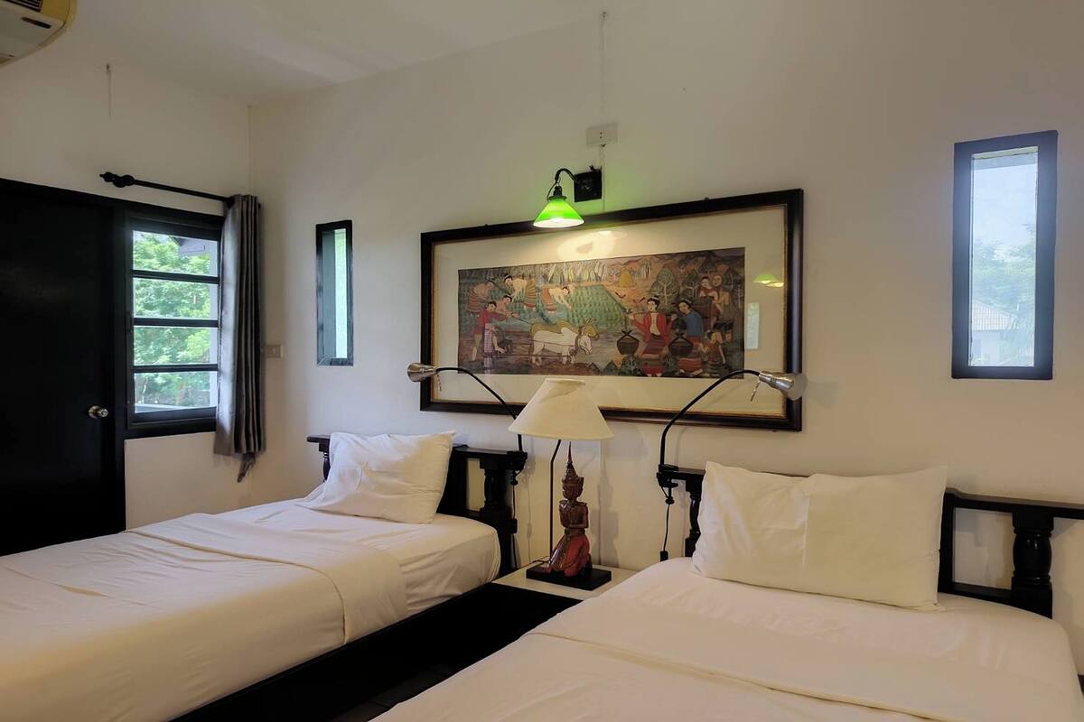 Habitación de hotel con dos camas, un cuadro en la pared y una ventana con cortinas.