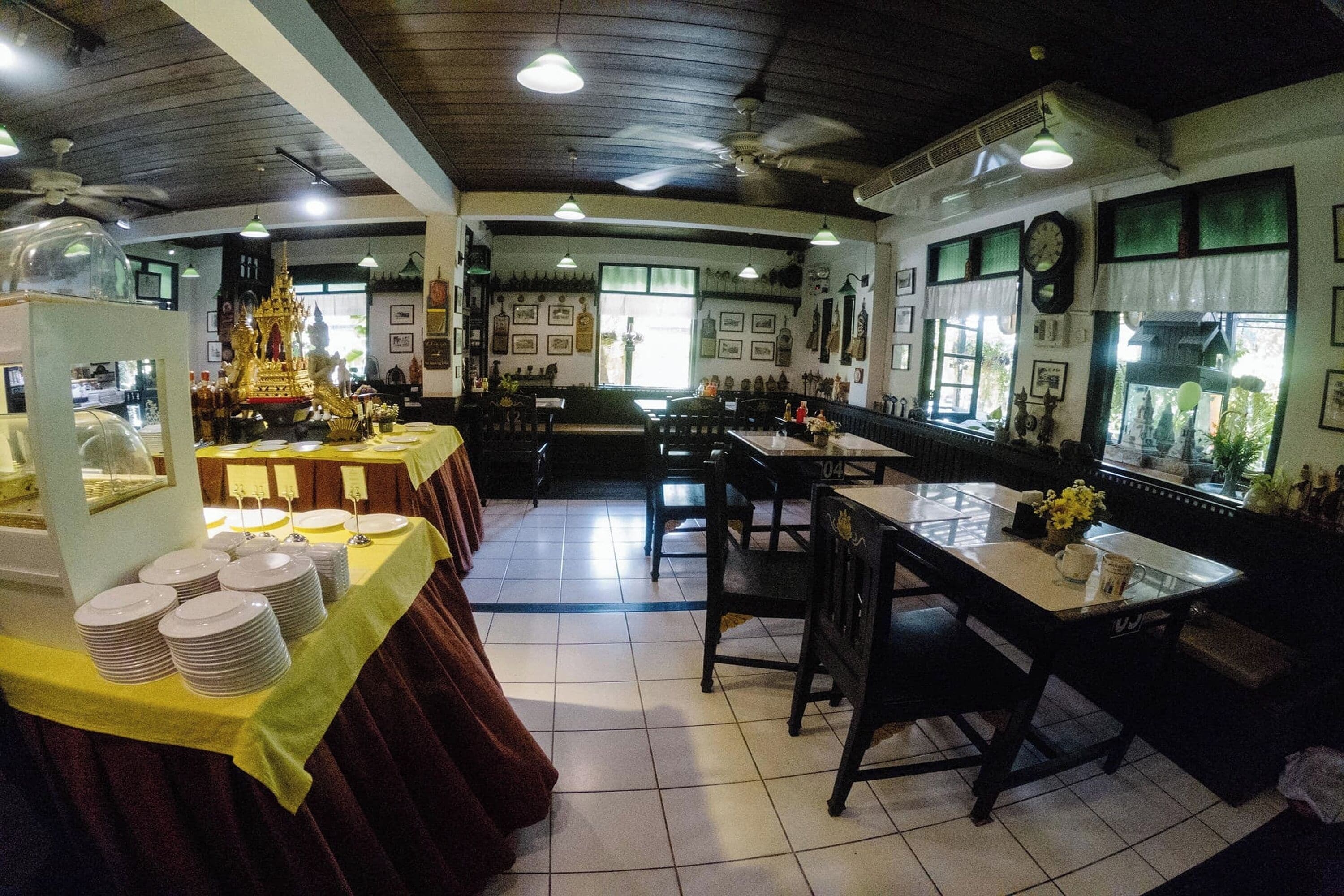Een restaurant met een klassiek interieur, met een centrale eetruimte met tafels en stoelen, een buffet aan de linkerkant en een keuken zichtbaar door de ramen.