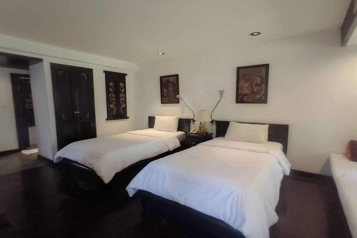 Una habitación de hotel moderna con dos camas individuales, piso oscuro y obras de arte en las paredes.