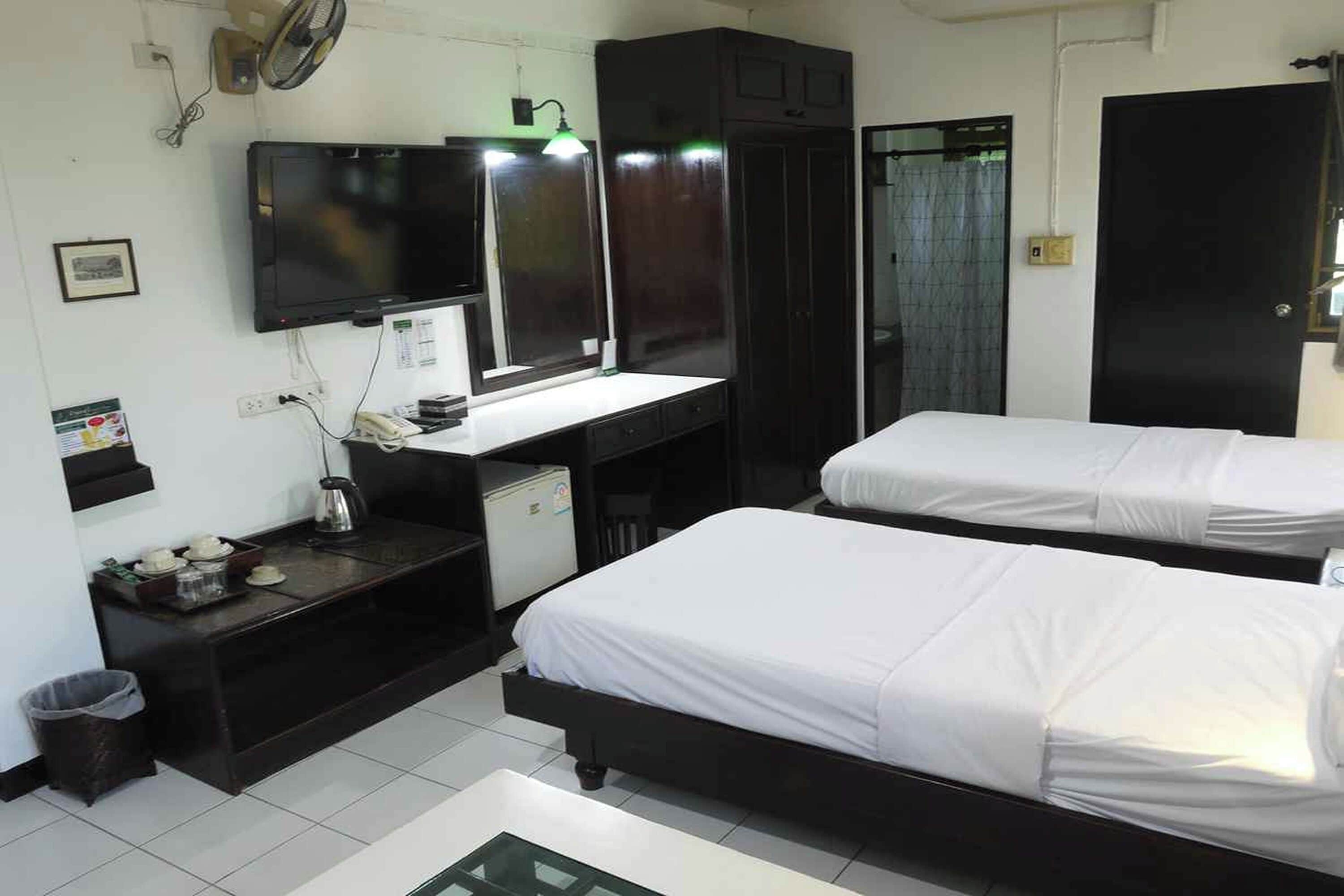 Een hotelkamer met twee bedden, een bureau met een televisie, een spiegel en een kledingkast.