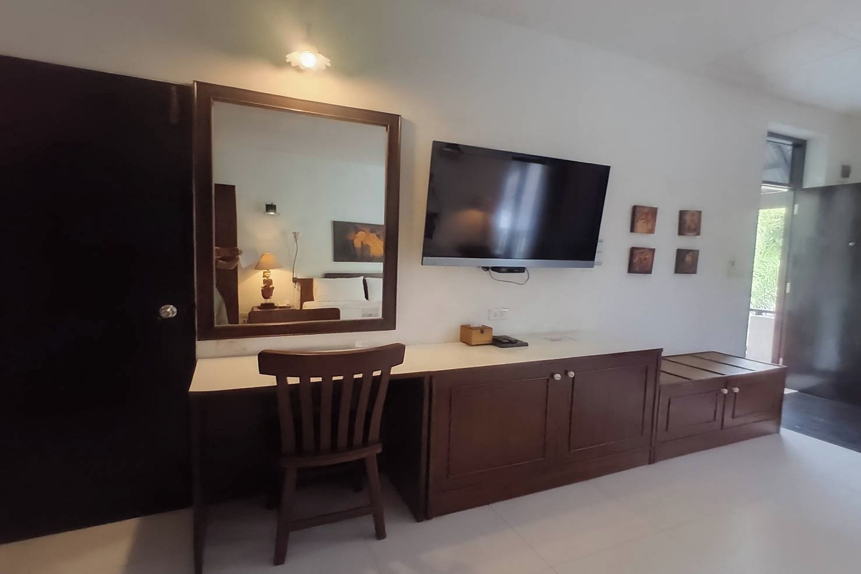 Une chambre moderne dotée d’un grand miroir, d’un téléviseur à écran plat, d’un bureau en bois et d’une armoire.