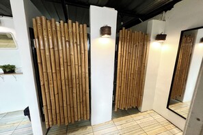 A room with bamboo partitions, a large mirror, and a small plant on a shelf. - Orchid Hostel Near Bumrungrad Hospital and Nana Market (Bangkok)
